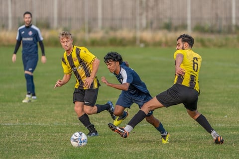 Young soccer players in yellow and blue jerseys competing for the ball during a youth football match on a grass field